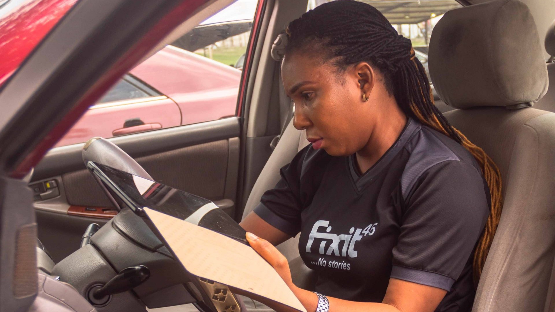 A woman sitting in the driver's seat of a car is waiting for her friends near Lekki Novare Mall.