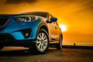 Blue car parked with sunset in the background, a perfect scene to remind owners about summer car care.