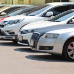 Closeup of front side of cars parking in outdoor parking lot beside the street beside the street in bright sunny day.